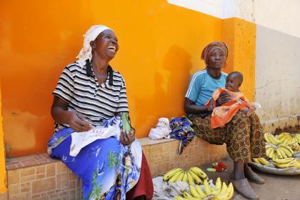 Two African women sitting on the ground selling fruits in the market. 