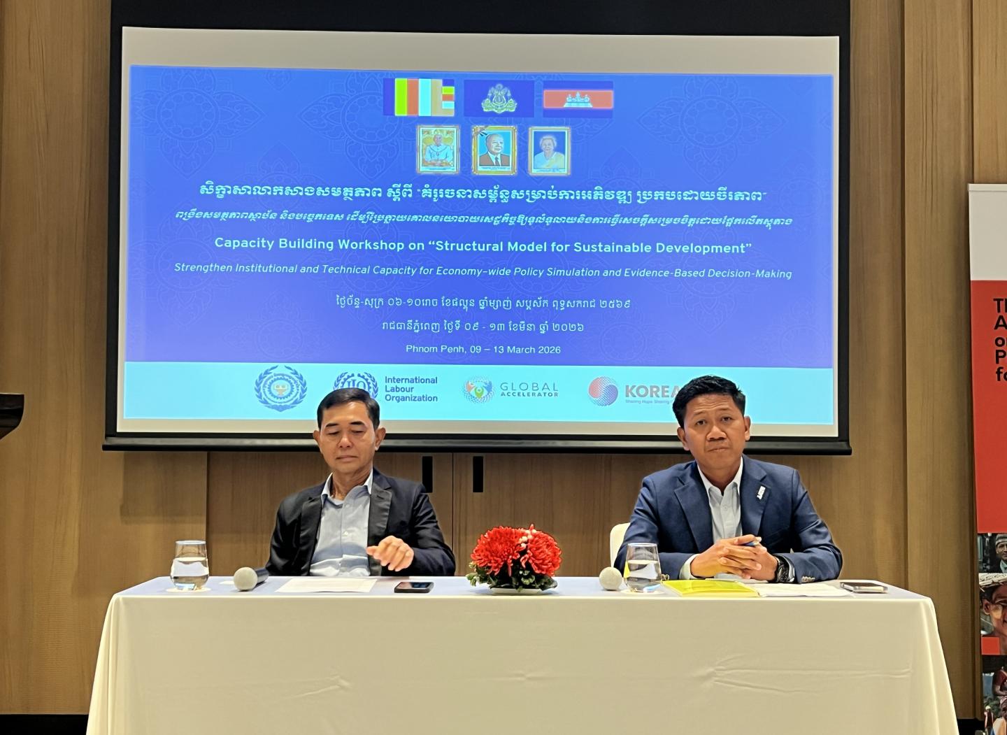 Two men sitting in front of a screen at an event