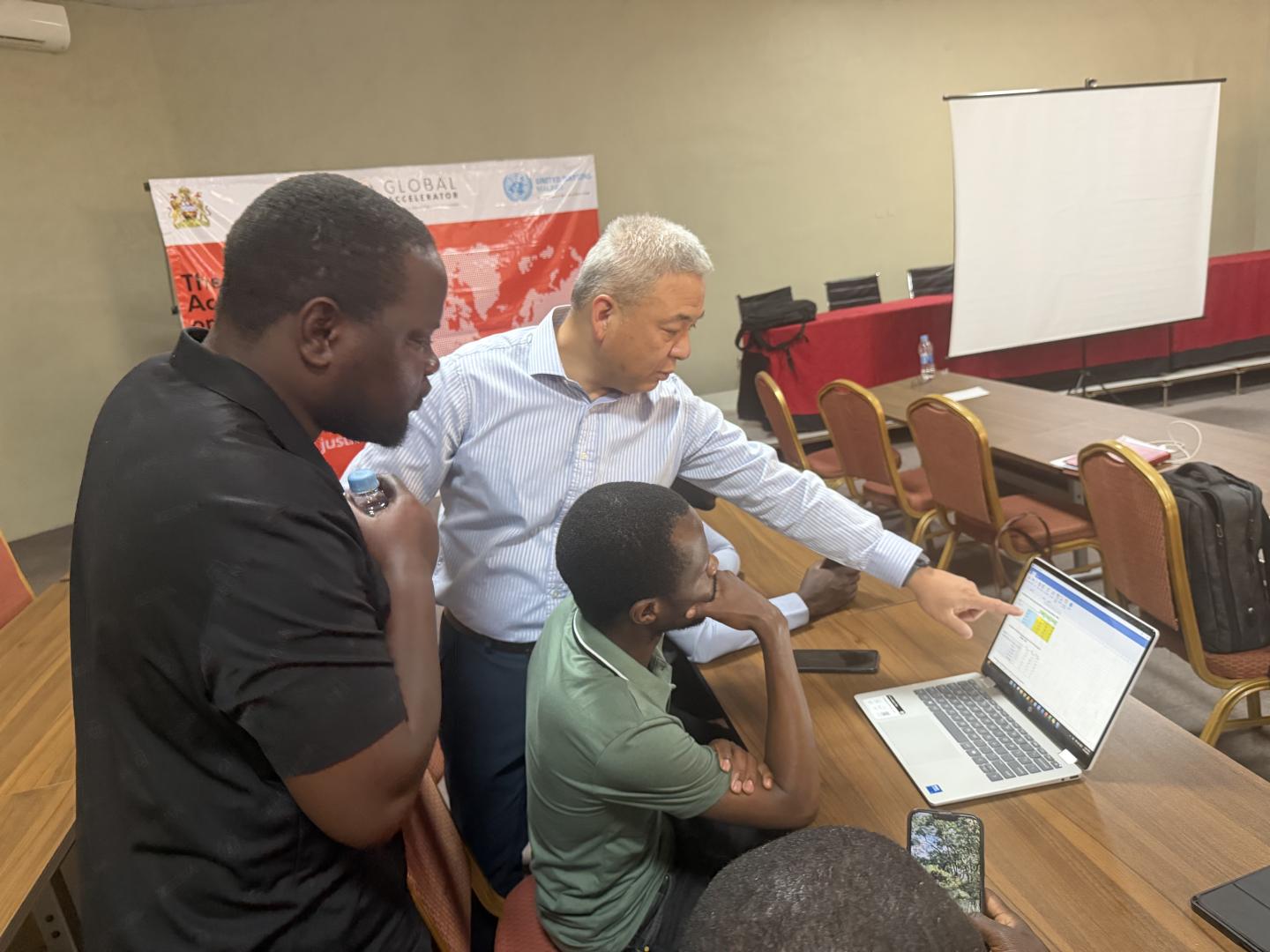 Three men around a computer
