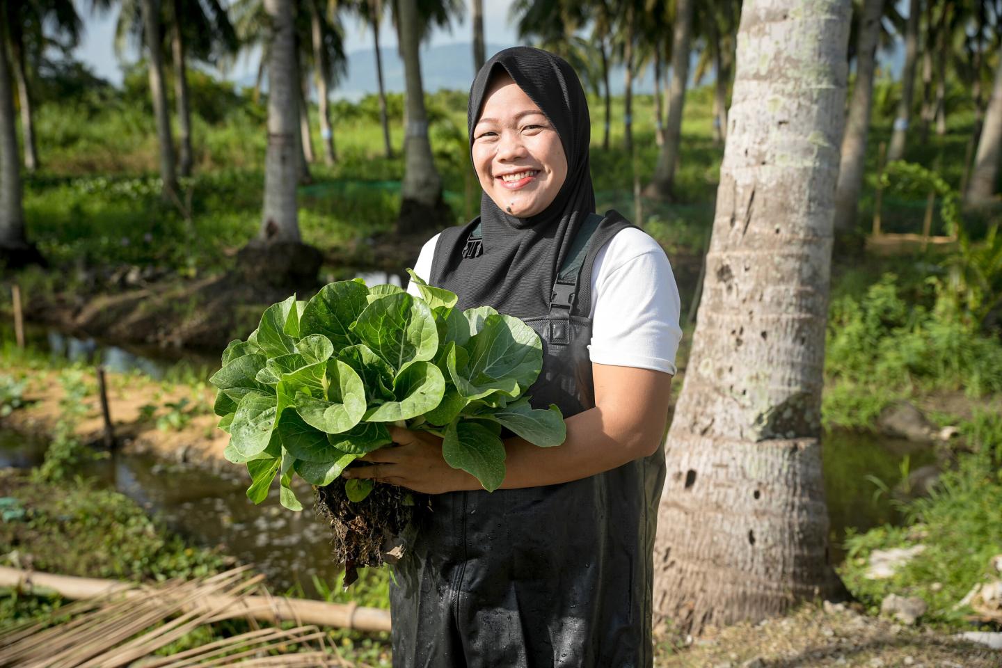 A woman holding freshly harvested leafy vegetables on a farm in the Philippines