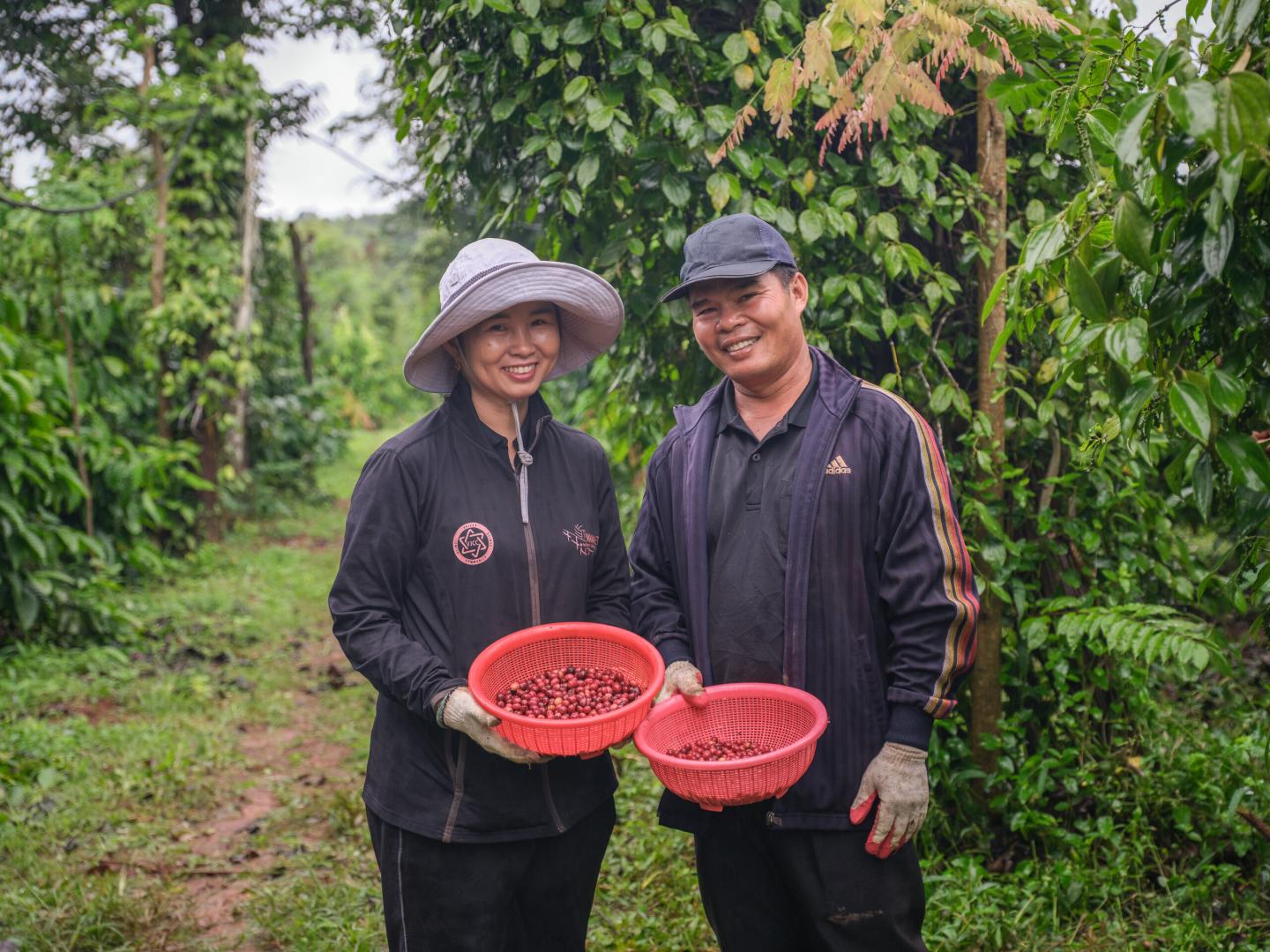 Two coffee farmers holding baskets of freshly picked coffee cherries in Viet Nam